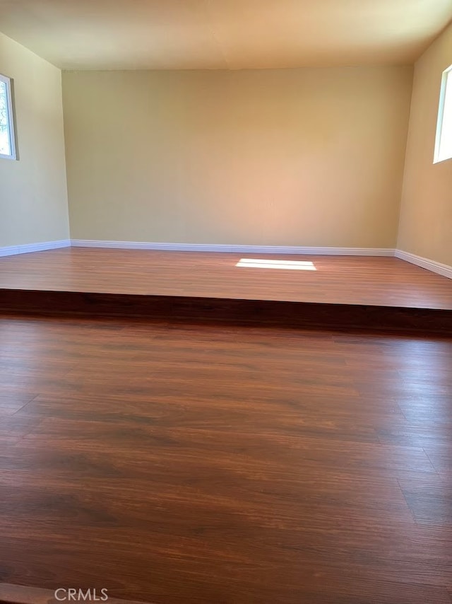 spare room with plenty of natural light and dark hardwood / wood-style flooring