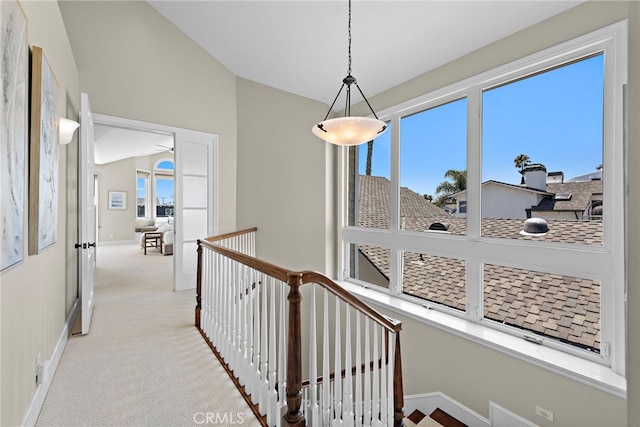 hall with lofted ceiling, light carpet, and a wealth of natural light