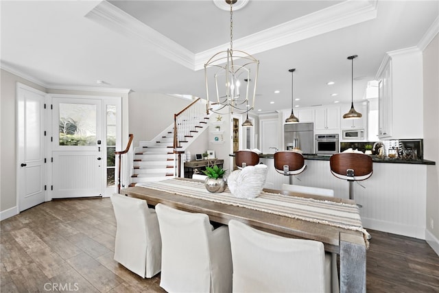 dining room with crown molding, dark hardwood / wood-style flooring, a raised ceiling, and a chandelier