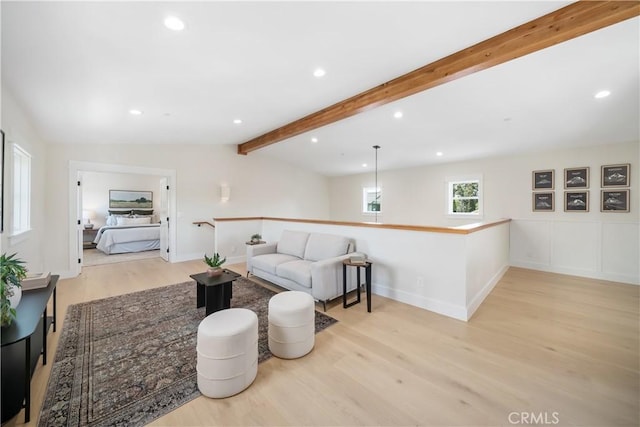 living room featuring vaulted ceiling with beams and light hardwood / wood-style flooring