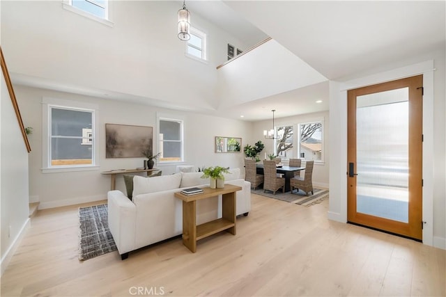 living room featuring a high ceiling, an inviting chandelier, and light hardwood / wood-style floors