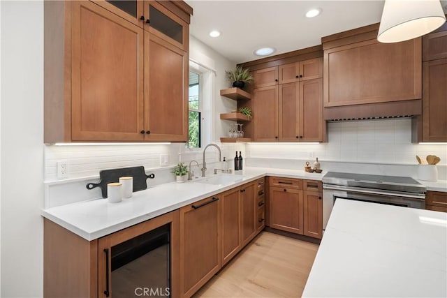 kitchen featuring sink, stainless steel range with electric cooktop, light wood-type flooring, light stone countertops, and decorative backsplash