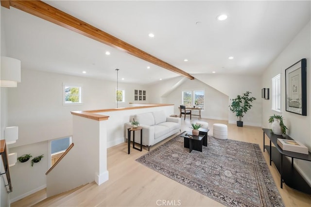 living room with light hardwood / wood-style flooring and vaulted ceiling with beams