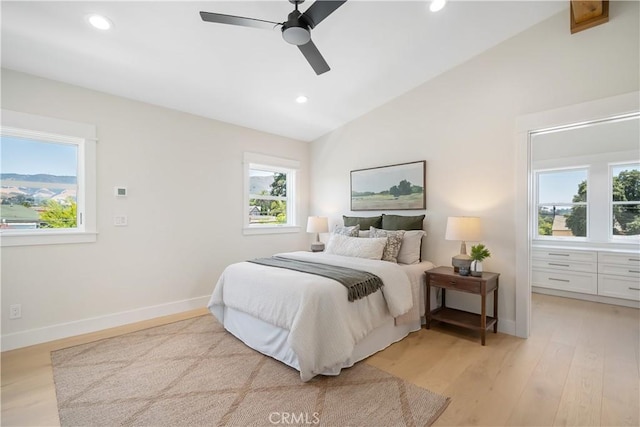 bedroom featuring multiple windows, lofted ceiling, ceiling fan, and light hardwood / wood-style floors