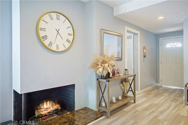 foyer entrance with light wood-type flooring and a multi sided fireplace