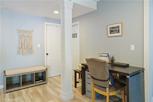 office with light wood-type flooring and decorative columns