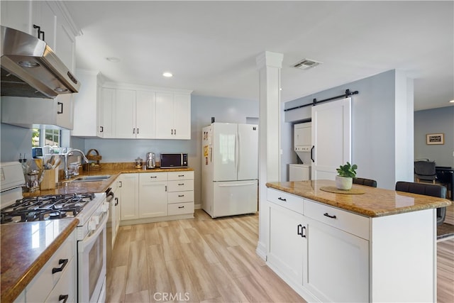 kitchen featuring a barn door, white appliances, range hood, light hardwood / wood-style flooring, and sink