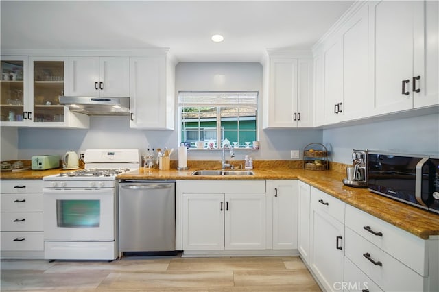 kitchen featuring white cabinetry, stone countertops, stainless steel appliances, light wood-type flooring, and sink