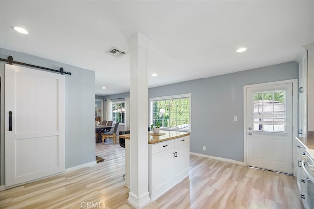 kitchen with light stone countertops, white cabinetry, light hardwood / wood-style floors, and a barn door