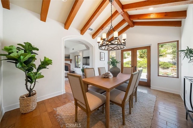 dining space with beamed ceiling, french doors, hardwood / wood-style flooring, and a chandelier