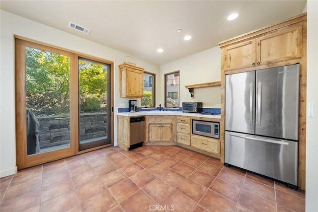 kitchen with light brown cabinets, light tile patterned floors, sink, and appliances with stainless steel finishes