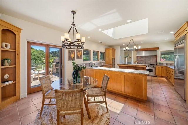 dining area with light tile patterned floors, a skylight, an inviting chandelier, and sink