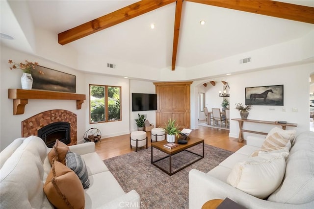 living room with high vaulted ceiling, an inviting chandelier, light hardwood / wood-style flooring, a fireplace, and beam ceiling