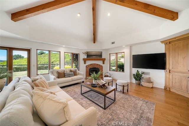 living room with beam ceiling, a fireplace, high vaulted ceiling, and light hardwood / wood-style flooring