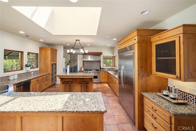 kitchen featuring a healthy amount of sunlight, high end appliances, kitchen peninsula, and a kitchen island