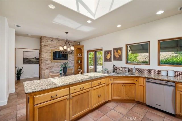 kitchen featuring kitchen peninsula, stainless steel dishwasher, sink, light tile patterned floors, and a notable chandelier