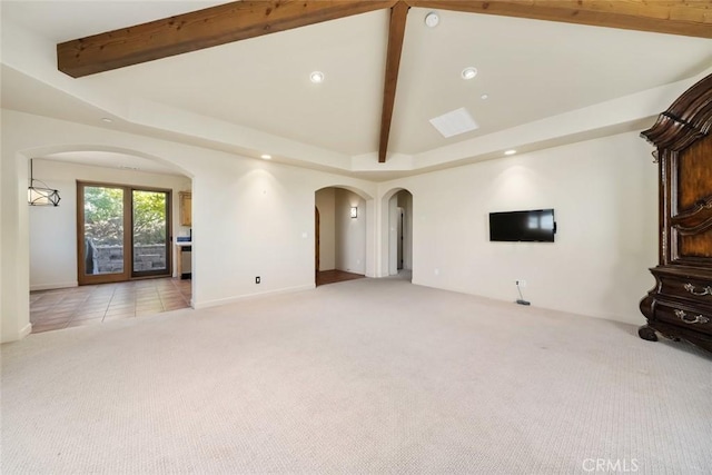 unfurnished living room featuring vaulted ceiling with beams and light colored carpet