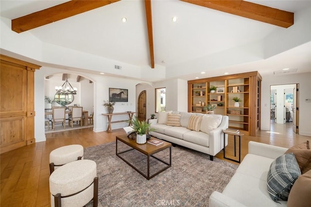 living room featuring a healthy amount of sunlight, beam ceiling, and light hardwood / wood-style flooring