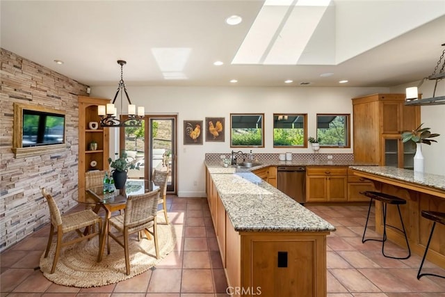 kitchen with kitchen peninsula, a skylight, light stone counters, decorative light fixtures, and an inviting chandelier