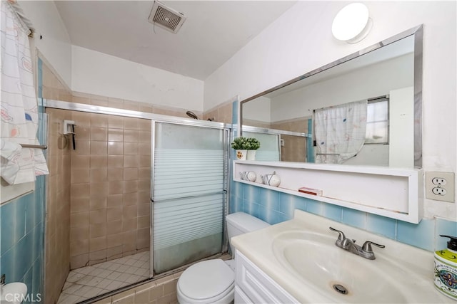 bathroom featuring tile walls, a shower with shower door, vanity, and toilet