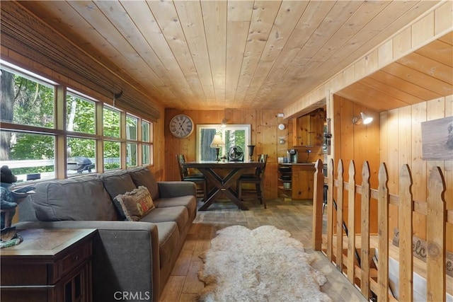 living room with wood ceiling, wooden walls, and light hardwood / wood-style flooring