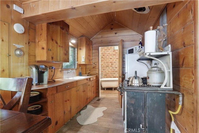 kitchen with vaulted ceiling, sink, wooden walls, light hardwood / wood-style flooring, and wooden ceiling