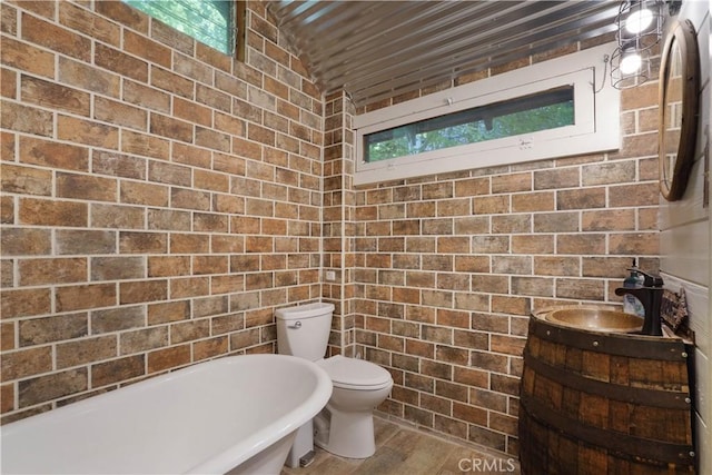 bathroom featuring toilet, vanity, lofted ceiling, a bath, and hardwood / wood-style flooring