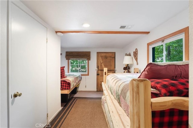 bedroom featuring beamed ceiling and multiple windows