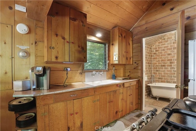 kitchen with vaulted ceiling, light hardwood / wood-style flooring, wood walls, and sink