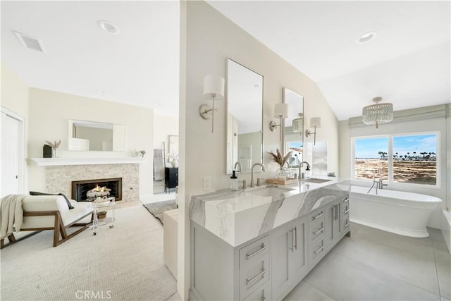 bathroom featuring vanity, an inviting chandelier, a bath, and vaulted ceiling