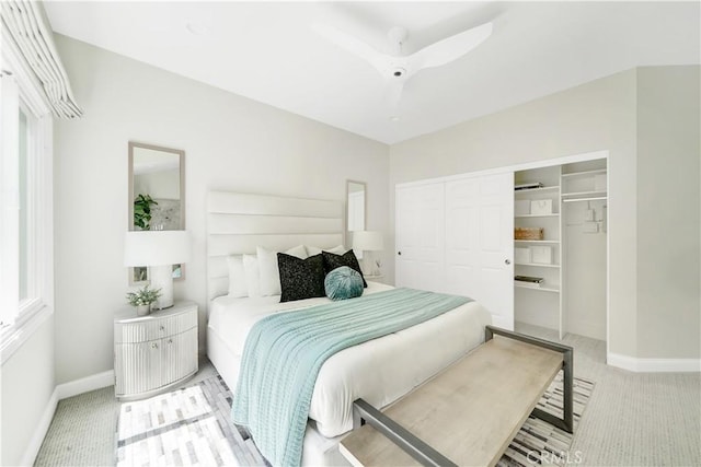 bedroom featuring ceiling fan, light carpet, and a closet