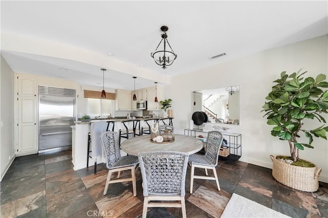 dining room with stone tile floors, visible vents, baseboards, and stairway