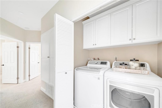 clothes washing area with separate washer and dryer, light colored carpet, and cabinet space
