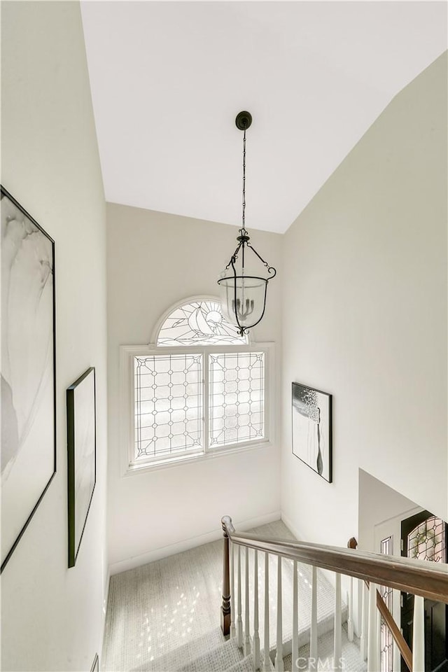 stairs featuring a chandelier and vaulted ceiling