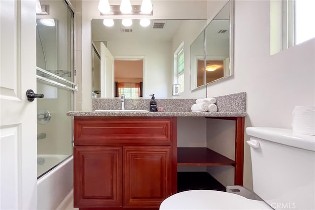 full bathroom with vanity, bath / shower combo with glass door, and toilet