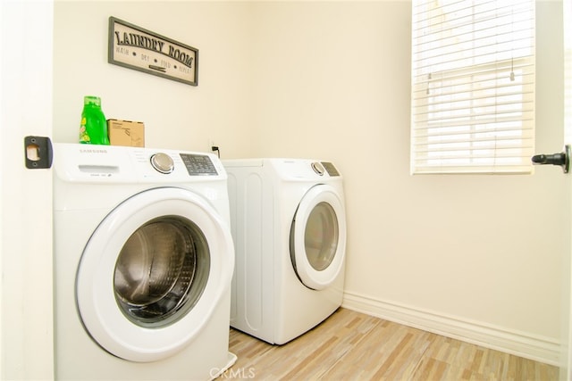 clothes washing area featuring light wood-type flooring and separate washer and dryer