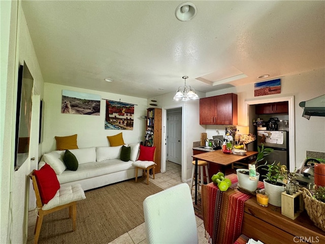 living room featuring a notable chandelier, a textured ceiling, light tile patterned flooring, and sink