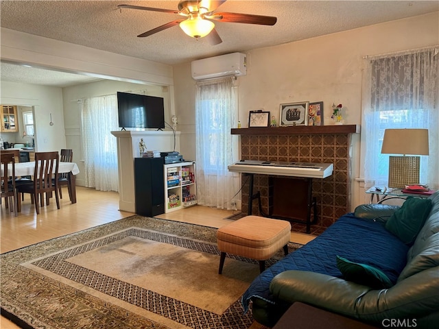 living room with ceiling fan, a wall mounted AC, a textured ceiling, a fireplace, and hardwood / wood-style floors