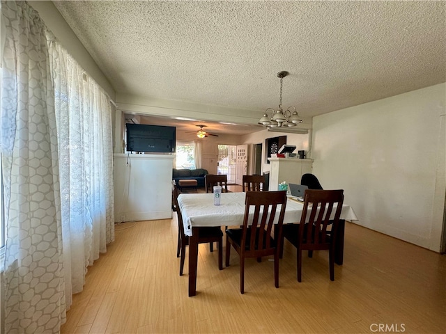 dining space featuring ceiling fan with notable chandelier, light hardwood / wood-style floors, and a textured ceiling