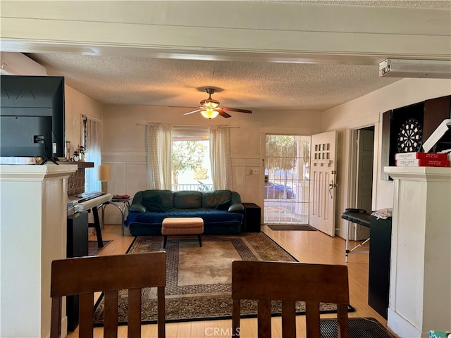 living room with a textured ceiling, light hardwood / wood-style floors, and ceiling fan