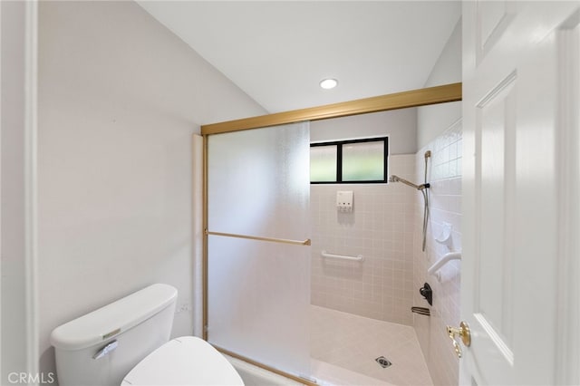 bathroom featuring lofted ceiling, toilet, and a shower with shower door