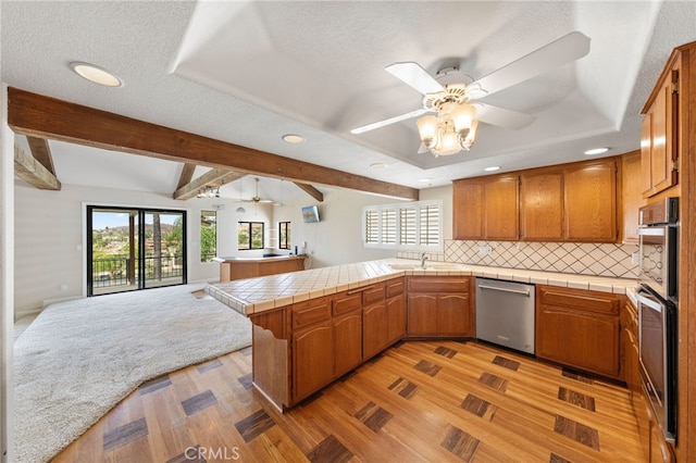 kitchen with dishwasher, a textured ceiling, tile counters, light hardwood / wood-style floors, and kitchen peninsula