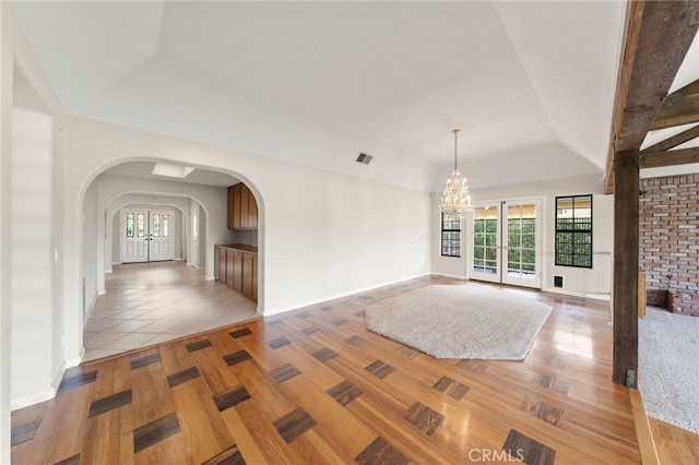 empty room with light hardwood / wood-style floors and an inviting chandelier