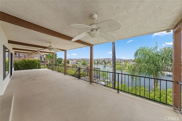 view of patio with ceiling fan, a water view, and a balcony