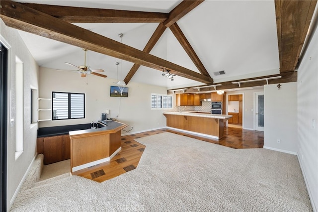 kitchen with beamed ceiling, plenty of natural light, kitchen peninsula, and light hardwood / wood-style flooring