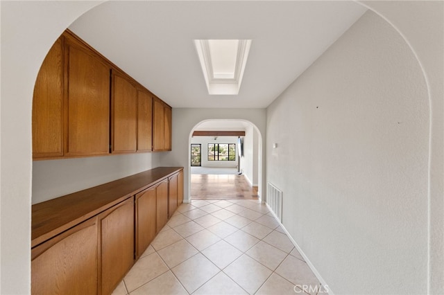 hallway with light tile patterned floors and a skylight