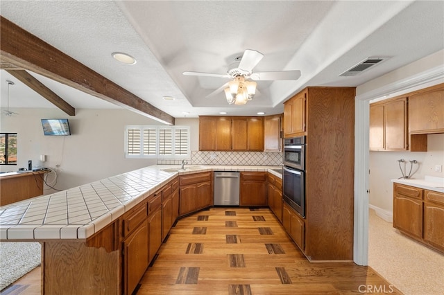 kitchen featuring tile countertops, ceiling fan, kitchen peninsula, and appliances with stainless steel finishes