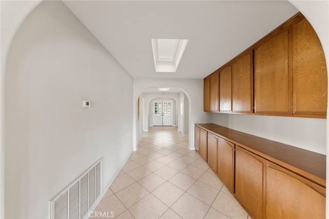 hallway featuring a skylight and light tile patterned flooring