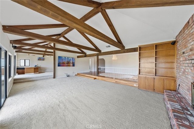 unfurnished living room featuring lofted ceiling with beams, ceiling fan, carpet floors, and brick wall