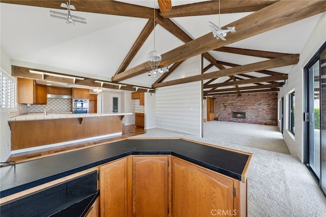 kitchen with plenty of natural light, beam ceiling, light colored carpet, and decorative backsplash